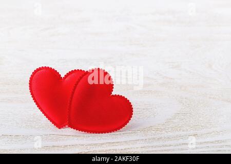 Zwei rote Seide Valentine Herzen auf einem weißen Holz- strukturierten Hintergrund. Konzept Liebe, Valentinstag. Grußkarte mit kopieren. Vorderansicht. Stockfoto