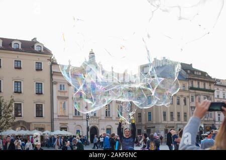 Die Menschen beobachten, wie ein Mann im Rynek Glowny (Hauptmarktplatz) im Zentrum von Krakow (Krakow), Polen, riesige Blasen erzeugt Stockfoto