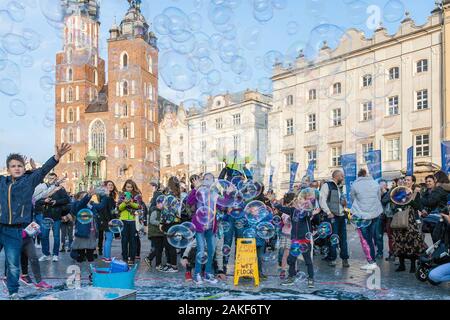 Die Menschen beobachten, wie ein Mann im Rynek Glowny (Hauptmarktplatz) im Zentrum von Krakow (Krakow), Polen, riesige Blasen erzeugt Stockfoto