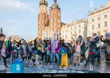 Die Menschen beobachten, wie ein Mann im Rynek Glowny (Hauptmarktplatz) im Zentrum von Krakow (Krakow), Polen, riesige Blasen erzeugt Stockfoto