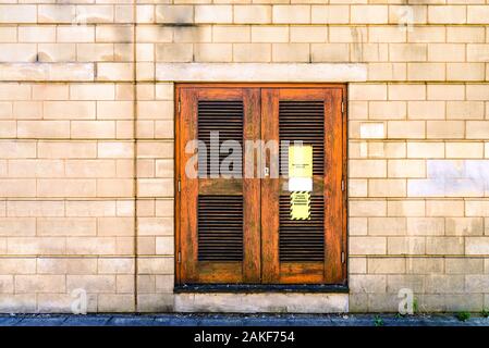 Gefahr Hochspannung Zeichen auf hölzernen Tür auf Stein mauer in England Großbritannien Stockfoto