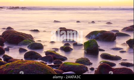 Meer Wasser verschwommen durch lange Exposition und bemoosten Steinen - Seascape Stockfoto