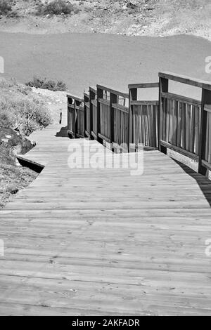 Holz- Gehweg mit Geländer am Strand. Schwarz/Weiß-Bild Stockfoto