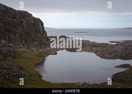 Ansicht der grönländischen Küste in der Nähe von Qaqortok mit Eisberg am Horizont Stockfoto