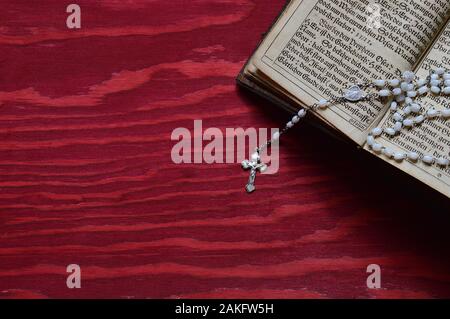 Rosary mit sehr altem altem Buch in altdeutscher Schrift auf rotem Holztisch Stockfoto