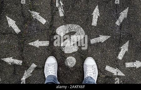 Person, die auf der Straße mit Fragezeichen und Pfeil Markierungen weisen in verschiedene Richtungen, Entscheidungsfindung Konzept Stockfoto