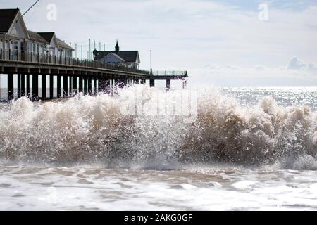 Große Wellen krachen am Strand mit Pier im Hintergrund Stockfoto