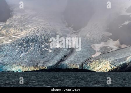 Ein riesiger Gletscher, der von nebligen Bergen herabkommt - eine fantastische Landschaft in der Arktis Stockfoto