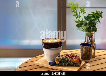 Eine Tasse Kaffee mit einem Stück veggie Torte auf einem Tisch, verschwommenen Hintergrund Stockfoto