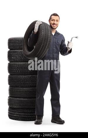 In voller Länge Porträt einer Automechaniker in einer Uniform mit einem Autoreifen und einen Schraubenschlüssel auf weißem Hintergrund Stockfoto