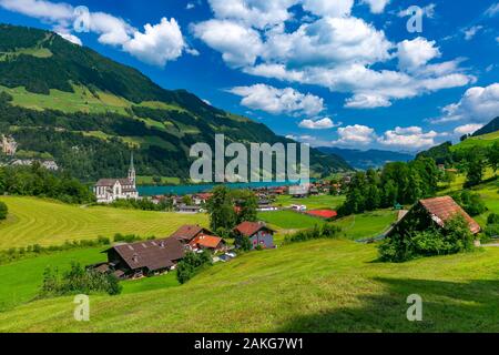 Katholische Kirche, traditionelle und moderne Häuser an der See im Schweizer Dorf Lungern Lungernsee im sonnigen Sommertag, Obwalden, Schweiz Stockfoto