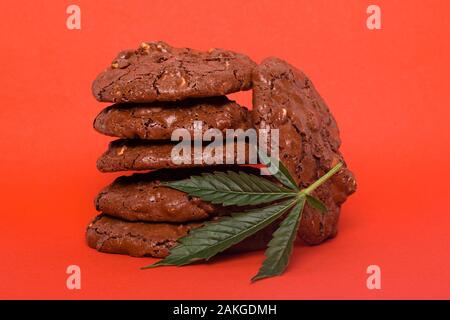 Cannabis Cookies auf roten Hintergrund. Hanf Blatt und Haferflocken Cookies mit Erdnüssen. Stockfoto