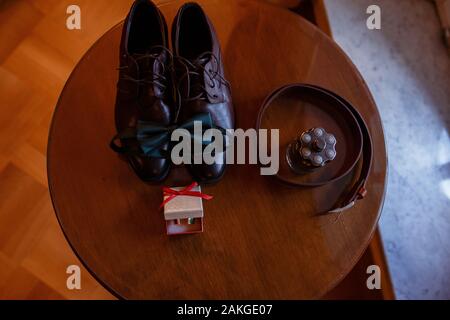 Bräutigam Hochzeit Zubehör. Schuhe, Schmetterling, Anstecker, Riemen, Herren Parfum, Manschettenknöpfe, Gürtel und Schuhe auf dem Tisch im Hotel Stockfoto