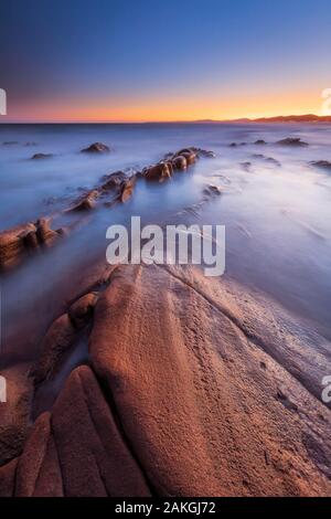 Frankreich, Var, Saint-Raphaël, Sonnenuntergang leuchten auf den Felsen von Péguière Strand mit dem Massif des Maures im Hintergrund Stockfoto