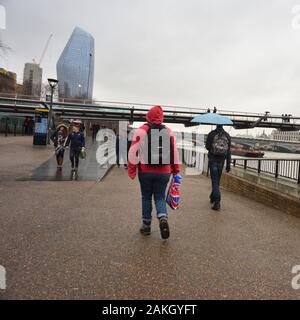 London, Großbritannien, 9. Januar 2020, Wetter. Dunkler Nachmittag in der Stadt, wenn starker Regen kommt. Menschen, die entlang der South Bank in Richtung Millennium Bridge in Mänteln und Regenschirmen Stockfoto