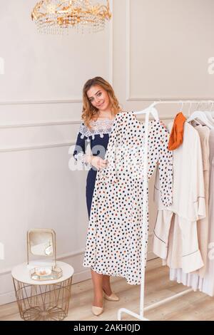 Junge Frau Wahl Polka-dot Dress unter Kleidung auf einem Rack private Showroom Stockfoto