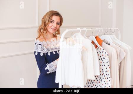 Junge Frau Wahl Kleidung auf einem Rack für die Partei Stockfoto