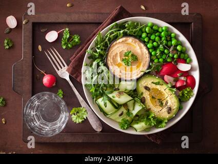 Gesund vegan Mittagessen Schüssel mit avocaco Gurke hummus Erbsen Rettich Stockfoto