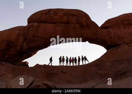 Namibia, Erongo, Spitzkoppe, Touristen unter dem Bogen Stockfoto