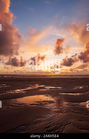 Starke goldenen Sonnenuntergang am Strand Porthtowan in Cornwall mit Reflexionen im nassen Sand und Wasser Pools Stockfoto