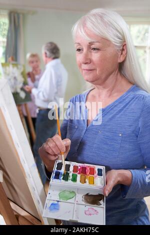 Seniorin Besucht Malklasse Mit Lehrer Im Hintergrund Stockfoto