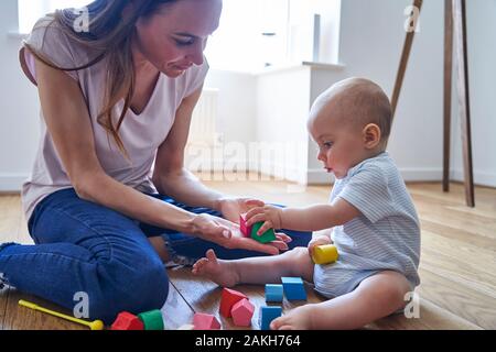 Mutter mit 8 Monate altem Baby Sohn Lernen durch Spielen mit farbigen Holzklötze zu Hause