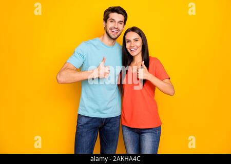 Foto von lustigen zwei Personen Paar in der Liebe Kerl lady Umarmen heben Daumen Finger zum Ausdruck Vereinbarung tragen Casual blau orange t-shirts Jeans isoliert Stockfoto