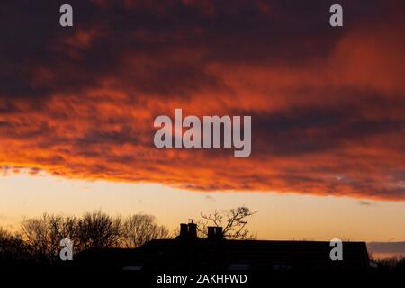 Wimbledon, London, UK. 9. Januar 2020. Clearing skies bei Sonnenuntergang nach schweren Nachmittag Regen, mit leuchtend bunte Sonnenlicht auf Wolken über die Dächer. Credit: Malcolm Park/Alamy Leben Nachrichten. Stockfoto