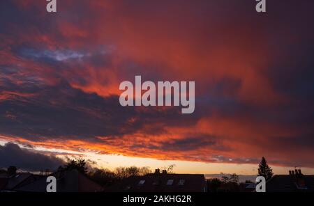 Wimbledon, London, UK. 9. Januar 2020. Clearing skies bei Sonnenuntergang nach schweren Nachmittag Regen, mit leuchtend bunte Sonnenlicht auf Wolken über die Dächer. Credit: Malcolm Park/Alamy Leben Nachrichten. Stockfoto