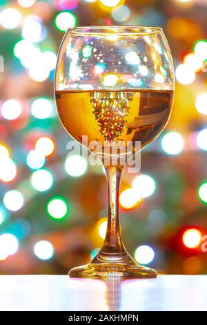Eine Tasse Weißwein auf einem Hintergrund von bunten Lichtern Stockfoto