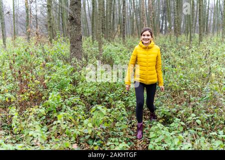 Frau in der hellen Jacke, die den Fallweg in Weißrussland hinunter geht Stockfoto