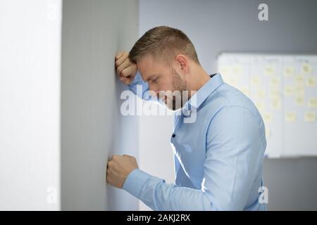 Portrait von Enttäuscht Geschäftsmann lehnte sich an der Wand im Büro Stockfoto