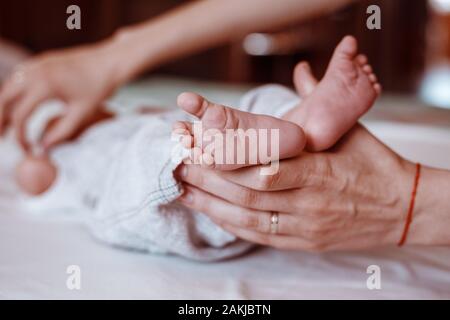 Baby Fuß in der Mutter. Winzige des neugeborenen Babys Füße auf weibliche geformten Hände Nahaufnahme. Mutter und ihr Kind. Happy Family Konzept. Schöne konzeptionelle imag Stockfoto