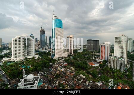Dramatische Himmel über Jakarta Skyline der Innenstadt, wo moderne Wolkenkratzer mit Armen Wohnviertel in Indonesien Hauptstadt Kontraste Stockfoto