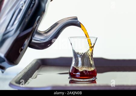 Kaukasische Mann gießen traditionellen türkischen Tee von Teekanne Stockfoto