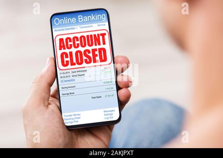 Person's Hand Handy mit Online Banking Anwendung und Konto geschlossen Nachricht auf dem Bildschirm Stockfoto