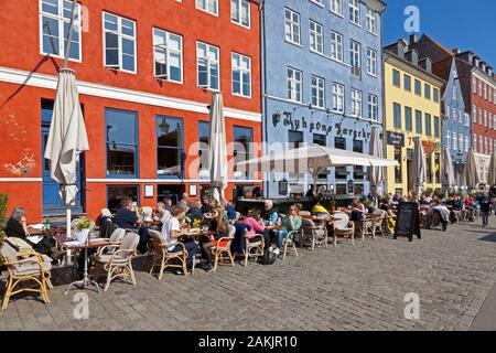 Die historischen Restaurants am Wasser in Nyhavn, Kopenhagen, locken Hunderte von Touristen und Kopenhagenern zu einem Mittagessen im Freien an einem sonnigen Frühlingstag. Stockfoto