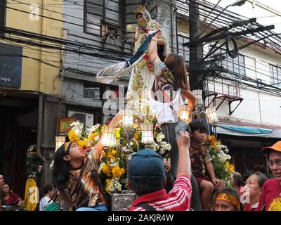 Eine Familie von Devotee abwischen Taschentücher auf die Jungfrau Maria Statue während der Veranstaltung. Filipinos in Quiapo in Manila für das Fest des Schwarzen Nazareners, ein Leben sammeln - Größe Statue eines leidenden Jesus Christus, der vom Kreuz gefallen. Katholische Gläubige tun ' pakaridad" einen Weg geben oder das gemeinsame Essen mit anderen und eine lange Prozession der Statue. Stockfoto