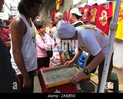 Devotees malen das Bild von Jesus Christus auf T-Shirts zu Interessenten während der Veranstaltung feilbot. Filipinos in Quiapo in Manila sammeln für das Fest des Schwarzen Nazareners, eine lebensgroße Statue eines leidenden Jesus Christus, der vom Kreuz gefallen. Katholische Gläubige tun ' pakaridad" einen Weg geben oder das gemeinsame Essen mit anderen und eine lange Prozession der Statue. Stockfoto