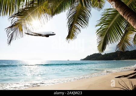 Flugzeug fliegt In wolkigen Himmel über Insel und Meer im Sommer in Seychellen Stockfoto