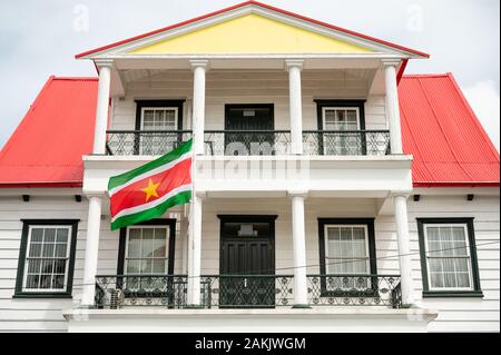 Nationalflaggen von Suriname, die vor einem Gebäude an der Canal Street in der Hauptstadt Paramaribo in diesem kleinen südamerikanischen Land fliegen Stockfoto