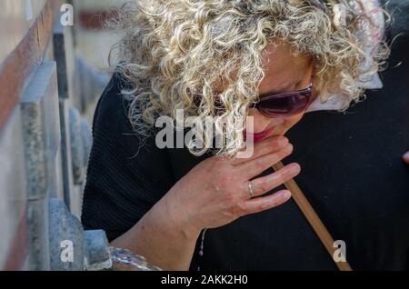 Blonde Frau mit locken Trinkwasser aus dem Auslauf eines Brunnens Stockfoto