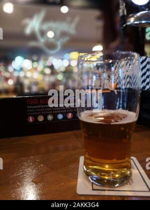 Ein 3/4 Pint Bier gegen eine außerhalb des Fokus Hintergrund mit der Quelle und Strohhalme im Fokus Stockfoto