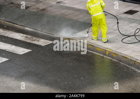 Arbeitnehmer Reinigung der Bürgersteig mit Wasser unter Druck. Wartung oder Reinigung Konzept Stockfoto