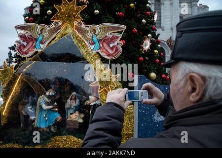 Moskau, Russland. 9. Januar, 2020 ein Mann nimmt Bilder auf einem Handy Weihnachten Krippe im Innenhof der Kirche Christi, des Erlösers im Zentrum von Moskau, Russland Stockfoto