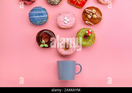 Bunte Krapfen mit Puderzucker und Kaffee Tassen auf Pastell rosa Hintergrund. Süße Krapfen. Flach Stockfoto