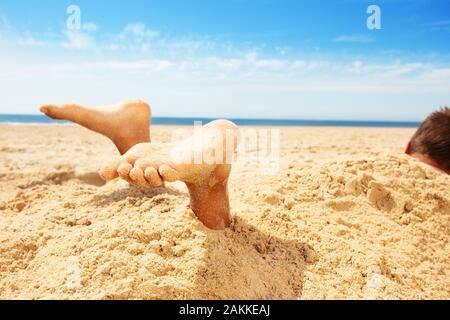 Beine und Füße boy von Sand in einem Spiel auf Meer bedeckt Stockfoto