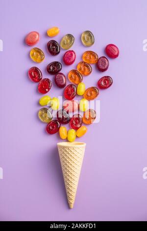 Süße bunte Bonbons in Eis auf Violett Hintergrund. Flache Ansicht. Stockfoto