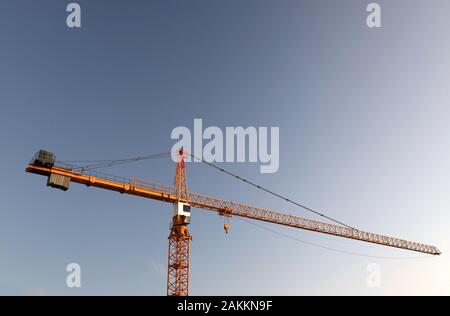 Baustelle: eine Nahaufnahme eines Turmdrehkrans auf einer Baustelle, sehr groß und hoch oben, Tower crane Control Station, Haken und Balance Gewicht. Stockfoto
