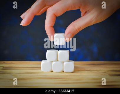 Holzwürfel auf dem Tischhintergrund, um eine Geschäftsnachricht mit einer Hand einzuschließen, die einen Block setzt Stockfoto